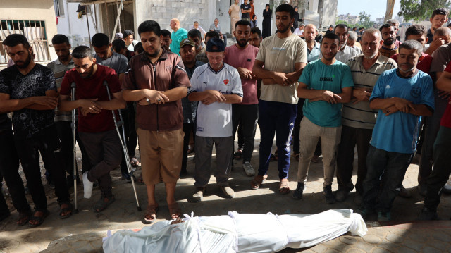 Des personnes prient devant le corps enveloppé d'un Palestinien, tué lors d'une frappe israélienne, lors de la procession funéraire à l'hôpital Al-Shifa dans la ville de Gaza, le 9 juillet 2025.