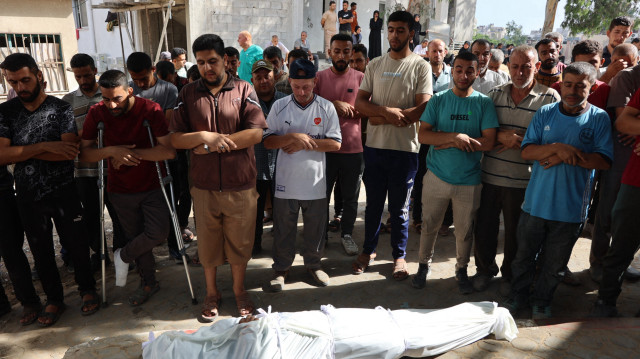 Des personnes prient devant le corps enveloppé d'un Palestinien, tué lors d'une frappe israélienne, lors de la procession funéraire à l'hôpital Al-Shifa dans la ville de Gaza, le 9 juillet 2025.