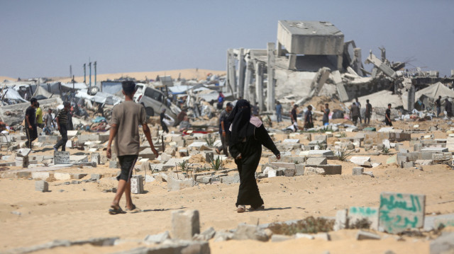 Les Palestiniens inspectent la destruction d'un camp de déplacés de fortune et du cimetière adjacent suite à une incursion de chars israéliens dans la zone de Khan Yunis, dans le sud de la bande de Gaza, le 11 juillet 2025.