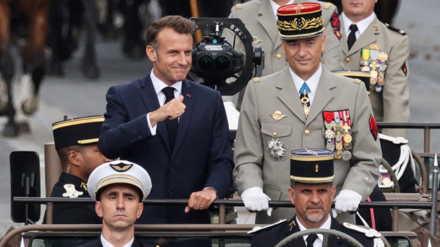 Le président français Emmanuel Macron (à gauche) et le chef d'état-major des armées françaises, le général Thierry Bukhard (à droite), passent les troupes en revue depuis leur voiture de commandement lors du défilé militaire annuel du 14 juillet sur les Champs-Élysées à Paris, le 14 juillet 2025.