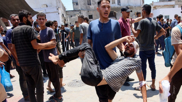 Un homme porte un Palestinien blessé lors d'une frappe israélienne, à l'extérieur de l'hôpital Maamadani (Baptiste) de la ville de Gaza, le 13 juillet 2025.