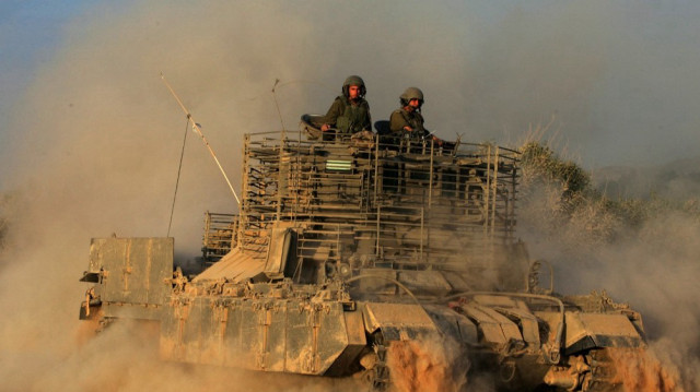 Des colons israéliens sont assis sur un véhicule blindé de transport de troupes pénétrant en territoire palestinien dans le nord de la bande de Gaza.