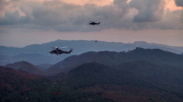 Des hélicoptères transportant de l'eau se dirigent vers un feu de forêt dans la province côtière syrienne de Lattaquié le 14 juillet 2025. L'agence de défense civile syrienne a déclaré le 13 juillet que les incendies de forêt dans l'ouest du pays, qui ont brûlé de vastes étendues de forêts et de terres agricoles et contraint à des évacuations, avaient été maîtrisés après 10 jours.
