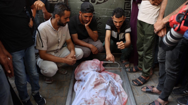 Des Palestiniens se lamentent devant un corps enveloppé, tué lors de frappes israéliennes nocturnes, à l'hôpital Al-Shifa dans la ville de Gaza, le 15 juillet 2025.