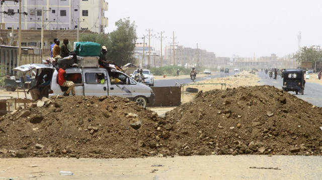Des personnes transportant leurs biens dans une camionnette passent devant des barricades de sable alors qu'elles retournent à Salha, au sud d'Omdurman, un jour après que l'armée soudanaise l'ait reprise aux Forces de soutien rapide (RSF), le 21 mai 2025.
