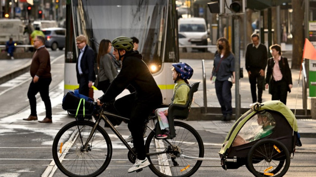 Un homme transporte ses enfants dans la circulation matinale du quartier central des affaires de Melbourne (CBD).