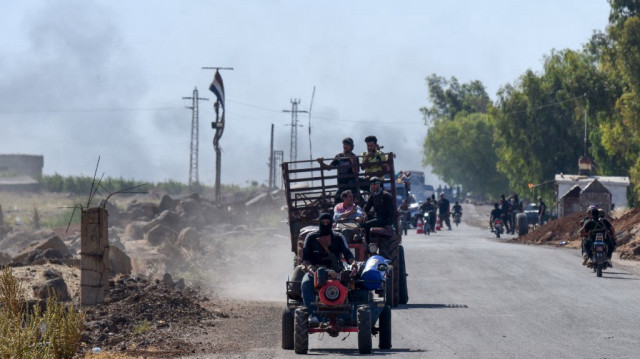 Des combattants de tribus bédouines conduisent sur une route du village d'al-Mazraa menant à la ville majoritairement druze de Soueïda, dans le sud de la Syrie, le 18 juillet 2025, alors que de la fumée s'élève à la suite de combats signalés.