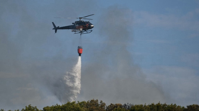 Un hélicoptère Airbus H125 largue de l'eau sur un incendie de forêt à Saint-Julien-les-Martigues, au nord-ouest de Marseille, dans le sud de la France, le 18 juillet 2025.