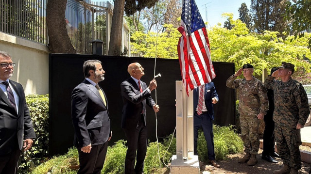 Le ministre syrien des Affaires étrangères Assaad al-Shibani (2ème à gauche) regarde l'envoyé spécial des Etats-Unis pour la Syrie, l'ambassadeur en Turquie Thomas Barrack, hisser le drapeau des Etats-Unis à la résidence de l'ambassadeur des Etats-Unis à Damas lors d'une cérémonie officielle qui s'est tenue le 29 mai 2025.