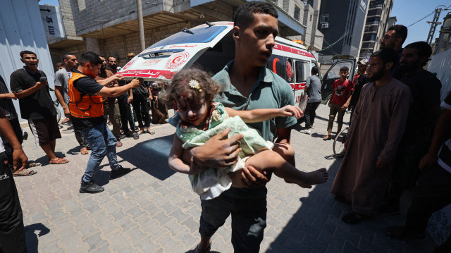 Un jeune Palestinien transporte une fille blessée lors d'une frappe israélienne sur un appartement du camp de réfugiés de Nuseirat à l'hôpital Al-Awda, dans le centre de la bande de Gaza, le 19 juillet 2025.
