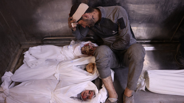 Un Palestinien pleure les corps enveloppés d'enfants tués lors des frappes israéliennes de la nuit, dans la morgue de l'hôpital Al-Shifa à Gaza City, le 15 juillet 2025.