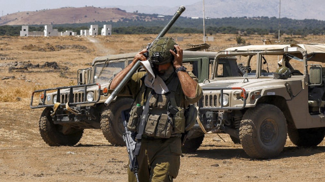 Un soldat de l'armée israélienne ajuste son casque alors qu'il marche pendant un exercice militaire dans une zone d'exercice spécial sur le plateau du Golan annexé par Israël, le 8 juillet 2025.