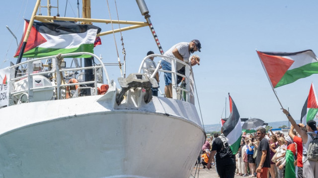 Des manifestants brandissant des drapeaux palestiniens se rassemblent près du navire "Handala" de la Flottille de la liberté avant son départ pour Gaza, dans le port de Syracuse, en Sicile, dans le sud de l'Italie, le 13 juillet 2025.