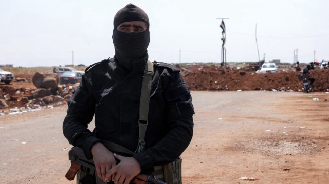 Un membre des forces de sécurité du gouvernement syrien se tient près d'une barrière de terre qu'ils ont créée comme tampon lors de leur déploiement à Busra al-Harir dans la province de Daraa, dans le sud de la Syrie, le 21 juillet 2025.