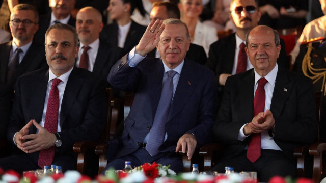 Le ministre turc des Affaires étrangères Hakan Fidan (G), le président turc Recep Tayyip Erdogan (C) et le dirigeant chypriote turc Ersin Tatar assistent à un défilé militaire commémorant l'invasion de Chypre par la Türkiye en 1974 et l'établissement de la « République turque de Chypre du Nord » (RTCN) autoproclamée, dans la partie nord de la capitale de l'île, Nicosie, le 20 juillet 2025.
