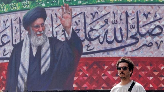 Un homme passe devant un panneau d'affichage représentant le guide suprême iranien, l'ayatollah Ali Khamenei, au centre de la place Valiasr de Téhéran, le 13 juillet 2025.