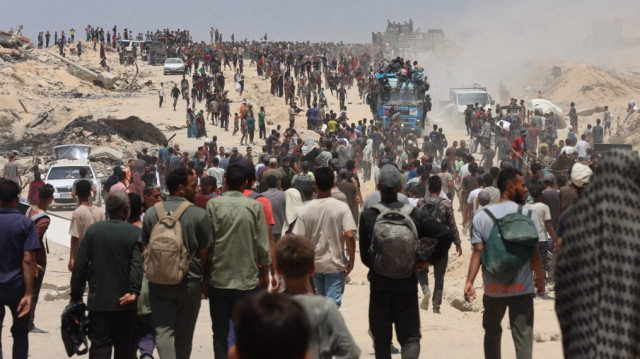 Le 22 juillet 2025, des personnes se dirigent dans la rue al-Rashid, à l'ouest de Jabalia, vers des camions transportant de l'aide humanitaire après leur entrée dans le nord de la bande de Gaza par le poste-frontière de Zikim, contrôlé par les Israéliens.