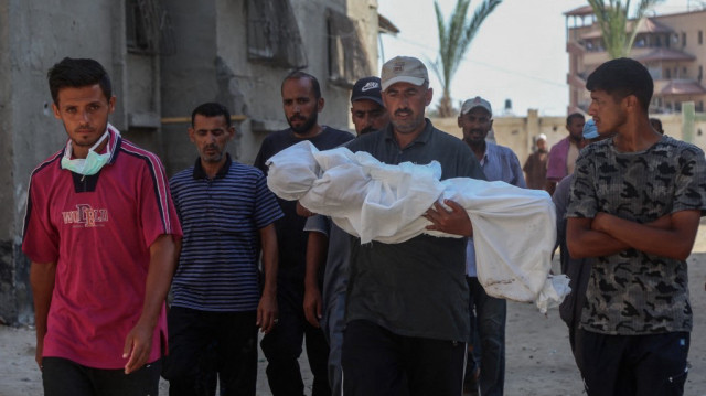 Des personnes en deuil transportent le corps recouvert d'un linceul du jeune Palestinien Abdul Jawad al-Ghalban, âgé de 14 ans, décédé de faim, avant son enterrement à l'hôpital Nasser de Khan Yunis, dans le sud de la bande de Gaza, le 22 juillet 2025.
