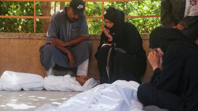 Les parents (L et C) du jeune Palestinien Abdul Jawad al-Ghalban, âgé de 14 ans, décédé de faim, pleurent devant son corps recouvert d'un linceul à l'hôpital Nasser de Khan Yunis, dans le sud de la bande de Gaza, le 22 juillet 2025.