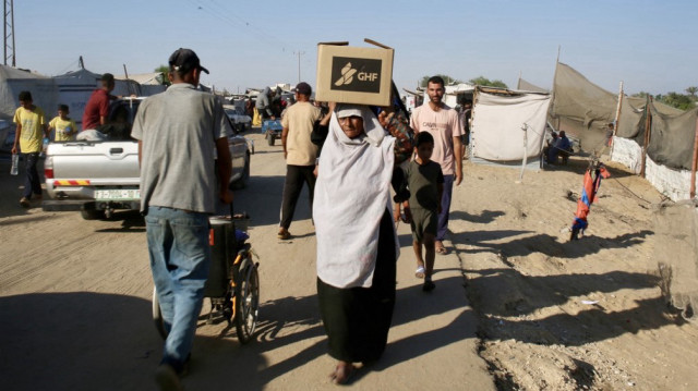 Une Palestinienne porte une boîte d'aide humanitaire sur la tête alors qu'elle se rend dans la rue al-Rashid, dans l'ouest de Jabalia, le 24 juillet 2025, après avoir reçu de l'aide humanitaire dans un centre de distribution situé dans le nord de la bande de Gaza.