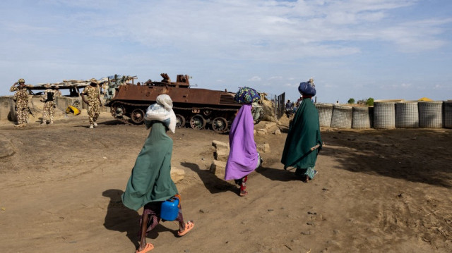 Des piétons passent devant un poste de contrôle pour sortir de Monguno, dans l'État de Borno, au Nigeria, le 4 juillet 2025. 