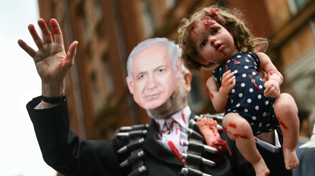 Un manifestant portant un masque à l'effigie du Premier ministre israélien Benjamin Netanyahou tient une poupée recouverte de peinture rouge, lors d'une "Marche nationale pour Gaza", dans le centre de Londres, le 8 juin 2024, appelant à "mettre fin au génocide" et à "cesser d'armer Israël".