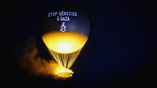 Un message "Stop au génocide à Gaza" est projeté sur la vasque olympique Paris 2024, conçue par le designer français Mathieu Lehanneur, alors qu'elle survole les jardins des Tuileries lors d'une action menée par Amnesty International, à Paris, le 26 juillet 2025.