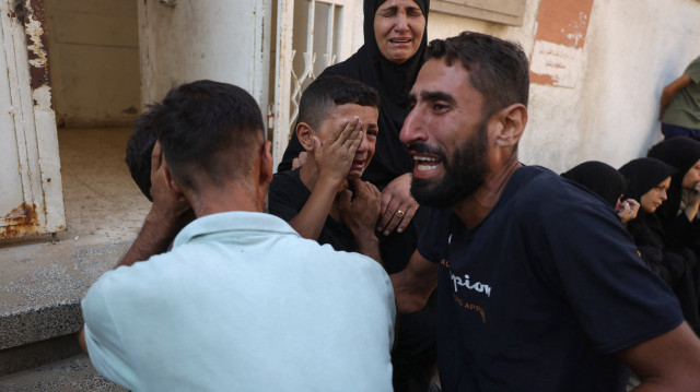 Les fils du journaliste palestinien Adam Abu Harbid, tué lors de frappes israéliennes nocturnes, sont réconfortés alors qu'ils pleurent leur père avant ses funérailles à l'hôpital Al-Shifa de Gaza, le 25 juillet 2025.