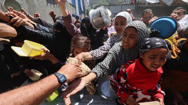 Les Palestiniens font la queue pour un repas chaud dans une cuisine caritative dirigée par le Programme alimentaire mondial (PAM) des Nations Unies au camp de réfugiés de Nuseirat dans le centre de la bande de Gaza le 26 avril 2025.