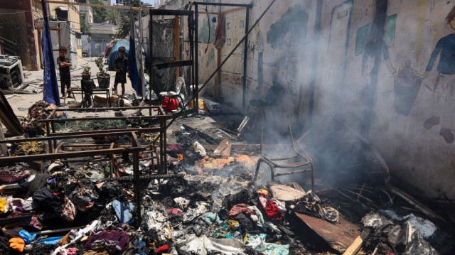 Les enfants regardent les débris couvants à l'école Mustafa Hafez, abritant les Palestiniens déplacés par la guerre, à la suite d'une frappe israélienne nocturne à Gaza City, le 3 juillet 2025, au milieu du conflit en cours entre Israël et le groupe militant palestinien du Hamas.