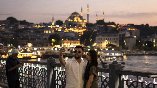 Un couple prend une photo au coucher du soleil sur le pont de Galata, dans la baie de la Corne d'Or, à Istanbul, en Turquie.
