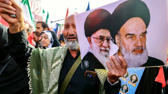 Un homme tient des portraits du guide suprême iranien, l’ayatollah Ali Khamenei (à droite), et de l’ancien guide suprême, l’ayatollah Ruhollah Khomeini, lors du cortège funèbre en hommage aux commandants militaires et aux scientifiques tués lors des frappes israéliennes au premier jour de la guerre, sur la place Enghelab (Révolution) dans la capitale Téhéran, le 28 juin 2025.