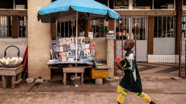 Un garçon passe devant des comptoirs avec des livres dans la rue à Ouagadougou le 7 octobre 2022.