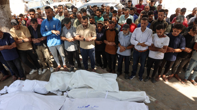 Des personnes en deuil prient devant les corps des victimes d'une frappe israélienne qui a touché l'école Mustafa Hafez, abritant des Palestiniens déplacés par la guerre, avant une procession funéraire à l'hôpital al-Shifa dans la ville de Gaza, le 3 juillet 2025, dans le cadre du conflit actuel entre Israël et le groupe militant palestinien du Hamas.