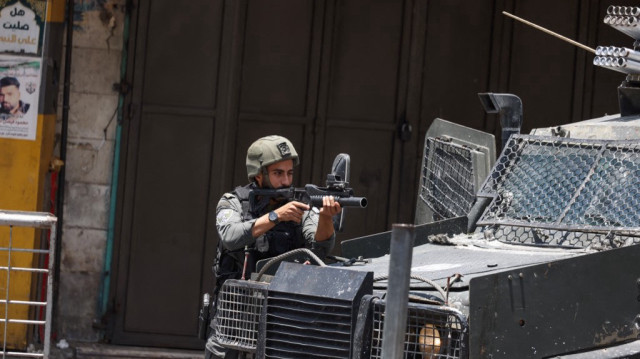 Un soldat israélien tire des gaz lacrymogènes sur des jeunes Palestiniens qui lancent des pierres sur son convoi militaire lors d'un raid dans la vieille ville de Naplouse, en Palestine occupée, le 10 juin 2025.