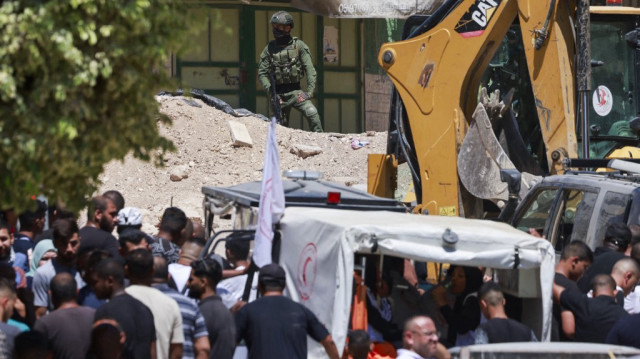 Un soldat israélien surveille les résidents palestiniens qui attendent à l'entrée du camp de Tulkarem, en Palestine occupée, lors d'une opération militaire le 6 juillet 2025.