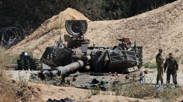 Des soldats colons se tiennent près d'un canon mobile de l'armée coloniales israélienne à la frontière israélienne avec la bande de Gaza.