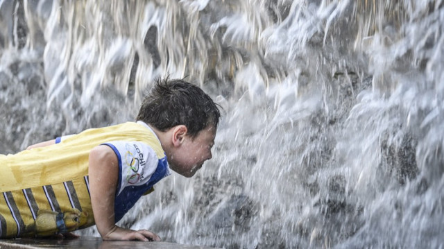 Un garçon se rafraîchit dans une fontaine à Moscou le 8 juillet 2025. La température à Moscou a atteint 32 degrés Celsius, (90F) et 36 centigrades (97F) sont attendus d'ici la fin de la semaine.