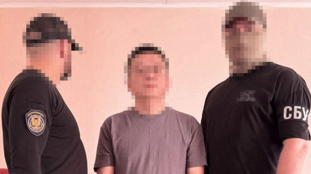 Cette image diffusée par le Service de sécurité de l'Ukraine (SBU) le 9 juillet 2025 montre un citoyen chinois (C) détenu par le Service de sécurité de l'Ukraine (SBU) à Kiev, dans le contexte de l'invasion de l'Ukraine par la Russie. Le SBU CI a arrêté à Kiev deux citoyens de la République populaire de Chine qui auraient tenté d'exporter illégalement vers la Chine de la documentation classifiée sur le système de missiles ukrainien RK-360MC Neptune.