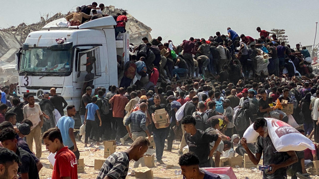 Des Palestiniens déplacés transportent des colis alimentaires après avoir pillé des camions transportant de l'aide humanitaire à Khan Yunis, dans le sud de la bande de Gaza, le 9 août 2025. Près de deux ans après le début de la guerre à Gaza, le Premier ministre israélien Benjamin Netanyahu fait face à une pression croissante pour obtenir un cessez-le-feu afin de sauver plus de deux millions de personnes de la famine et de libérer les otages détenus par les militants palestiniens.
