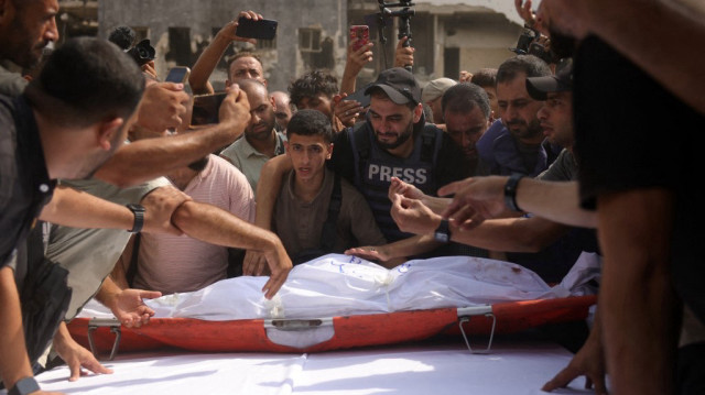 Les personnes en deuil déposent le corps du correspondant d'Al Jazeera Anas al-Sharif, tué avec d'autres journalistes lors d'une attaque israélienne nocturne contre leur tente à Gaza, sur une table avant le cortège funèbre à Gaza, le 11 août 2025.