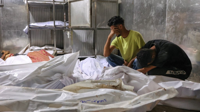 Les Palestiniens pleurent les corps recouverts d'un linceul des personnes tuées la veille alors qu'elles cherchaient de l'aide près de Zikim, à l'ouest de Beit Lahia, dans le nord de la bande de Gaza, à la morgue de l'hôpital Al-Shifa de Gaza City, le 10 août 2025.