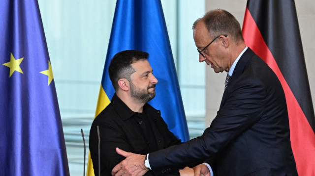 Le président ukrainien Volodymyr Zelensky (à gauche) et le chancelier allemand Friedrich Merz se serrent la main après avoir pris la parole lors d'une conférence de presse conjointe à l'issue d'une vidéoconférence des dirigeants européens avec le président américain sur la guerre en Ukraine, avant le sommet entre les dirigeants américain et russe, à Berlin, le 13 août 2025.