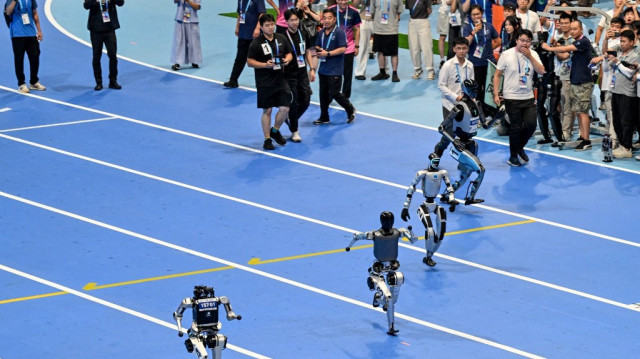 Des robots humanoïdes effectuent un sprint de 100 mètres lors de la cérémonie d'ouverture des Jeux mondiaux des robots humanoïdes à Pékin, le 14 août 2025.