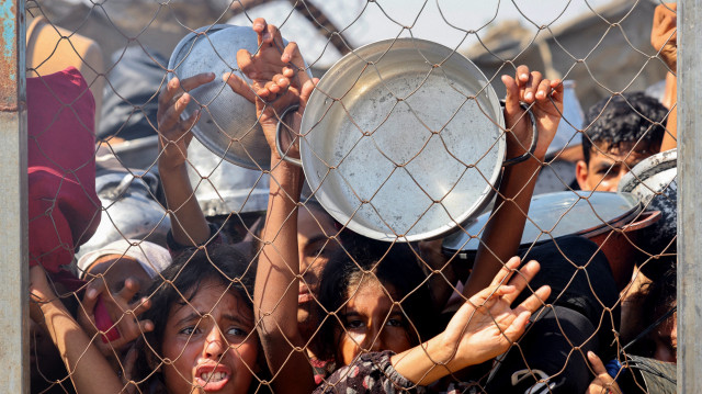 Des Palestiniens, principalement des enfants, se pressent pour recevoir un repas chaud dans une cuisine caritative du quartier de Mawasi, à Khan Yunis, dans le sud de la bande de Gaza, le 22 juillet 2025. 