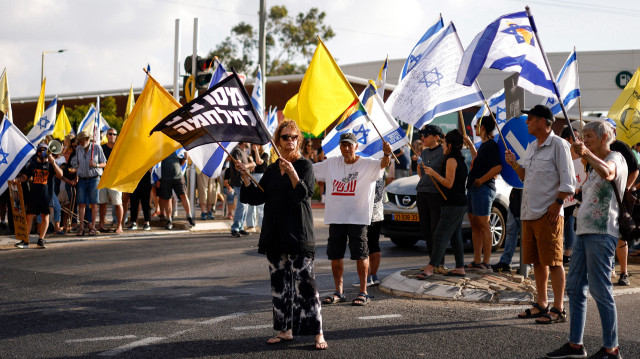Des Israéliens brandissent des drapeaux nationaux et jaunes lors d'une manifestation contre leur gouvernement pour exiger un accord visant à libérer les otages israéliens détenus dans la bande de Gaza par les militants du Hamas depuis le 7 octobre 2023, près de la ville de Kiryat Shmona, dans le nord du pays, le 17 août 2025.