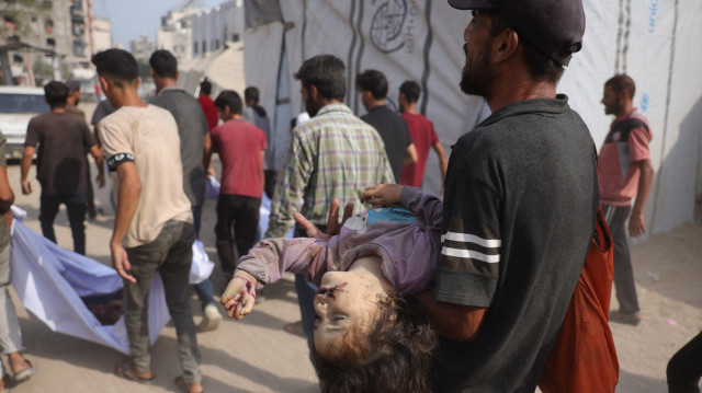 Un Palestinien transporte le corps d'une fillette de la famille Irhim, tuée lors d'une frappe israélienne tôt le matin dans le quartier de Zaitun, vers l'hôpital Al-Shifa de Gaza City, le 11 août 2025.