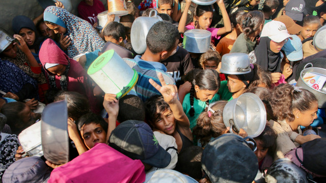 Un garçon palestinien fait le signe de la victoire alors qu'il se fraye un chemin dans la foule pour recevoir un repas chaud dans une cuisine caritative du quartier de Mawasi, à Khan Yunis, dans le sud de la bande de Gaza, le 22 juillet 2025.