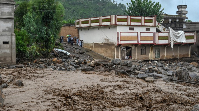 Des villageois (au centre, à gauche) se tiennent près d'un bâtiment alors que le niveau des eaux monte dans le district de Buner, dans la province pakistanaise de Khyber Pakhtunkhwa, le 18 août 2025.