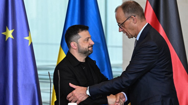 Le président ukrainien Volodymyr Zelensky (à gauche) et le chancelier allemand Friedrich Merz se serrent la main après avoir pris la parole lors d'une conférence de presse conjointe à l'issue d'une vidéoconférence des dirigeants européens avec le président américain sur la guerre en Ukraine, avant un sommet entre les dirigeants américain et russe, à Berlin, le 13 août 2025.